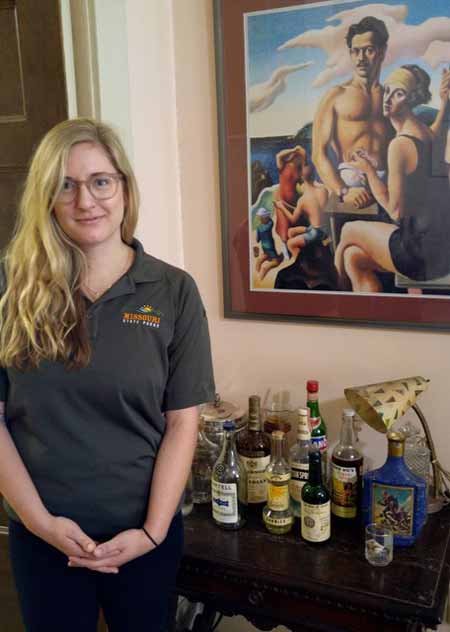 Katie Hastert, site interpreter, with original bar items, and 1922 self-portrait of Benton and his wife, Rita