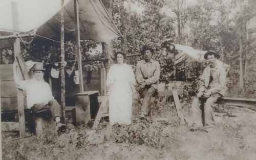 Four people in Tent ... Miners in early 1900s rest in their tent in the hills above Rush.