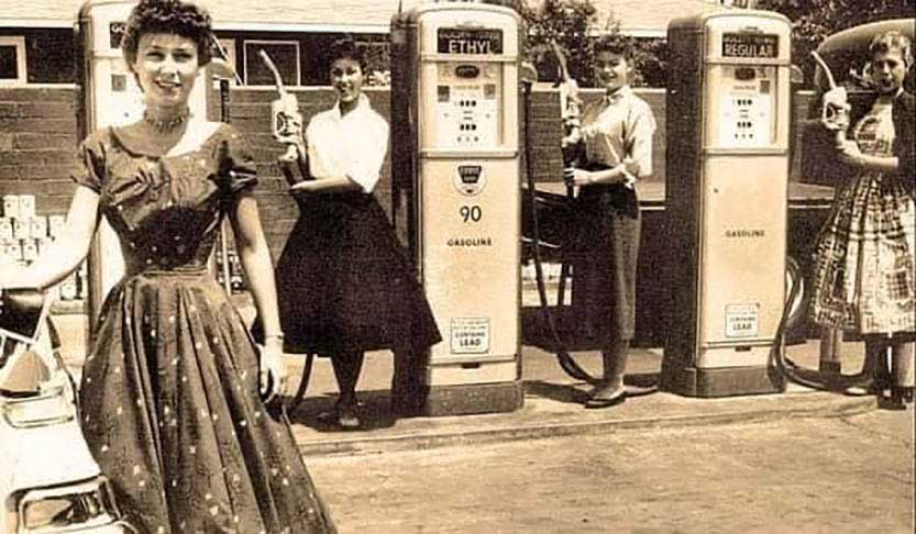 What better way to advertise your filling station than with lovely ladies? “Gas girls” pose at the pump in this midcentury photo. 